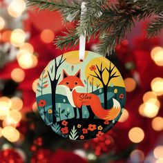 a christmas ornament with a fox on it hanging from a tree in front of lights