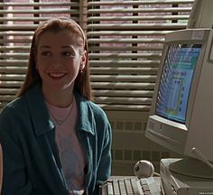 a woman sitting in front of a computer with a keyboard and monitor on her desk