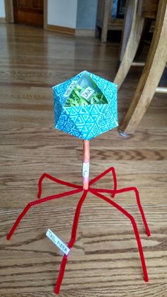 an origami spider made out of dollar bills on a wooden floor next to a chair