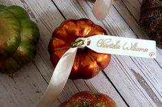 several different types of pumpkins on a white wooden surface with a name tag attached to them