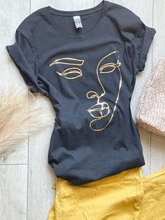 Description 100% cotton t-shirt. Black shirt with graphic outlined in gold. True to size. Sizes Women (S-XL) Neckline Options:  Crew or V-neck Processing This product will be created and shipped within 5-7 business days. Be sure to check out my other creations at www.canvasandcreationsus.etsy.com Trendy Gold T-shirt For Summer, Trendy Gold Summer T-shirt, Trendy Gold Crew Neck T-shirt, Gold Short Sleeve Tops With Graphic Print, Gold Graphic Print Short Sleeve Top, Gold Graphic Tee With Short Sleeves, Gold Graphic Tee Tops For Summer, Gold Short Sleeve Graphic Tee, Gold Graphic Print Short Sleeve T-shirt