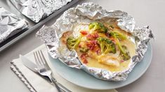 a plate topped with food covered in foil next to silverware and fork on top of a table