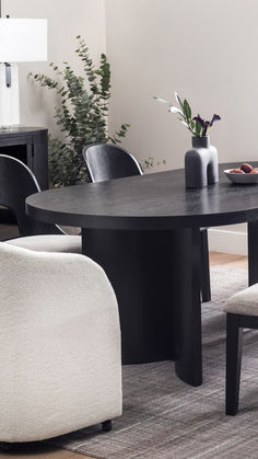 a round table with chairs around it and a vase on the table next to it