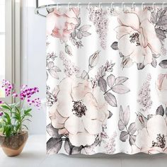 a white shower curtain with pink flowers on it next to a potted plant and window