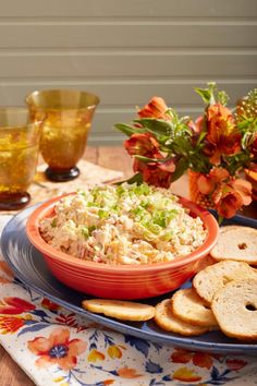 a bowl of coleslaw and crackers on a plate with flowers in the background