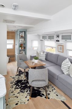 a living room filled with furniture next to a kitchen and dining room table on top of a hard wood floor