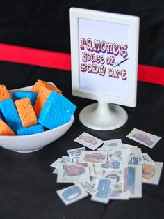 a bowl full of blue and yellow squares next to a pile of stickers