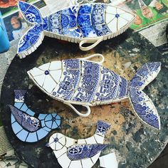 three blue and white fish shaped dishes sitting on top of a black table next to each other