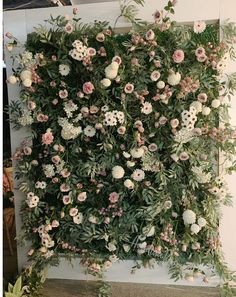 an arrangement of flowers and greenery on the wall