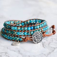 Genuine leather and turquoise jasper gemstones make up this classic boho style, three layer wrap bracelet. Always a favorite ~ and when you think bohemian, you think turquoise! Turquoise looks gorgeous on every skin tone. Give it a try and enjoy the versatility. 4mm (.157") diameter turquoise jasper gemstones Silver finished bamboo leaves motif button, about 16mm (5/8") in diameter Rust brown leather Signature Bluefish logo heart charm 34 - 39 cm/13.5 - 15.5" length 3 button loop adjustments to Classic Boho Style, Turquoise Wrap Bracelet, Bluish Green, Bead Leather, Three Layer, Leather Wrap Bracelet, Jasper Gemstone, Leather Wraps, Skin Tone