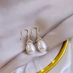 Best of both worlds! Iridescent pearls and clear cubic zirconia that capture the light from every angle with a perfectly translucent appeal come together to create a classy, sparkly and elegant pair of bridal earrings. The settings are gold / rhodium plated for a bright finish which enhances the intricate detailing and conveys a modern take on old elegance. Overall length of the earring is 1.5" (approx. 3.8cm). Width: 0.4" (approx. 1.2cm). Weight: 6g. Available in Yellow Gold and Silver with Whi Luxury Yellow Gold Pearl Bridal Earrings, Evening Pearl Jewelry In Diamond White, Diamond White Pearl Jewelry For Evening, Elegant Pearl Jewelry For Parties, White Crystal Earrings With Elegant Design For Party, Glamorous Pearl Drop Jewelry, Elegant Crystal Bridal Earrings With Pearl Drop, Elegant White Crystal Pearl Earrings, Glamorous Cubic Zirconia Pearl Drop Jewelry