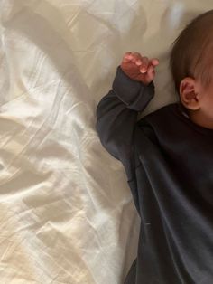 a baby laying on top of a white sheet