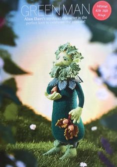 a knitted green man is standing in the grass with flowers on it's head