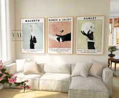 three posters hang on the wall above a white couch in a room with hardwood floors