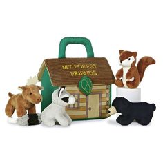 three stuffed animals are sitting in front of a small toy house with a bag on it