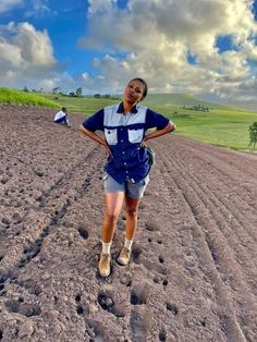 a woman standing in the middle of a dirt field