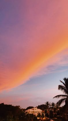 the sky is pink and purple as the sun sets in the distance behind some palm trees