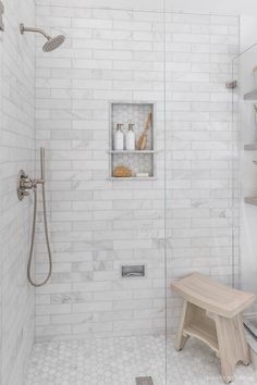 a walk in shower sitting next to a white tiled wall with shelves on each side