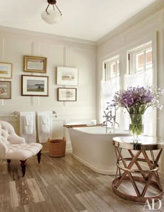 a bath room with a tub a chair and pictures on the wall