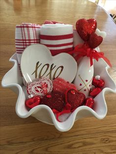 a bowl filled with valentine's day decorations on top of a wooden table