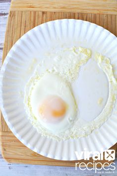 an egg on a paper plate sitting on a cutting board