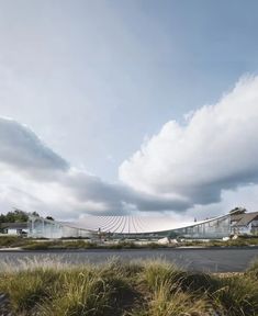 the building is surrounded by tall grass and clouds in the sky, with an empty parking lot on one side