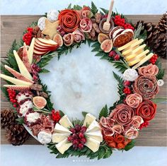 a wreath made out of fruit and flowers on a wooden board with pine cones, cinnamons and other holiday decorations