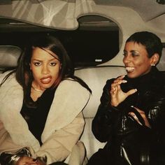 two women sitting in the back of a car with their mouths open and one holding a cell phone