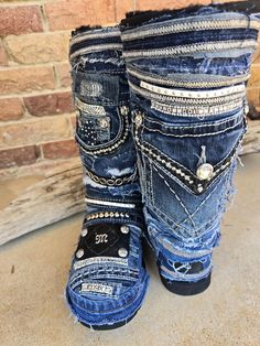 two pairs of blue jeans with studded accents and zippers on the bottom, sitting next to a brick wall