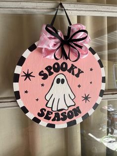 a wooden sign that says spooky season with a ghost on the front and pink background