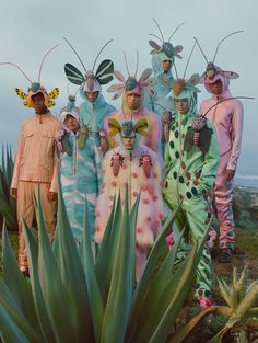 a group of people dressed in costume standing next to each other near a large plant