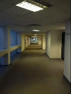 an empty hallway with no people or cars on the side and light coming from the ceiling