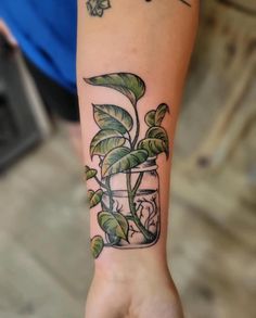 a person's arm with a plant in a jar tattoo on the left wrist