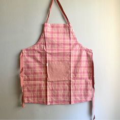 an apron hanging on the wall with a pink and white checkerboard pattern in it