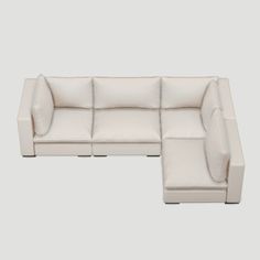 a white leather sectional sofa sitting on top of a gray floor