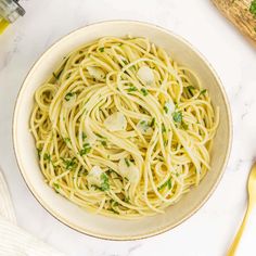 a bowl filled with pasta and parsley on top of a white marble countertop