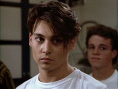 two young men standing next to each other in front of a mirror with one looking at the camera