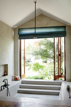 an image of a bathroom with steps leading to the tub and windows in front of it