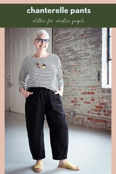 an older woman standing in front of a brick wall wearing black and white striped shirt