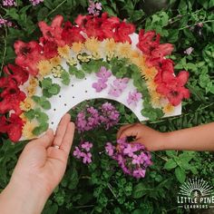 two hands are holding a paper plate with flowers on it and a rainbow in the middle