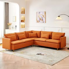 an orange sectional sofa sitting on top of a rug in a living room next to a window