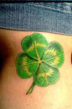 a green four leaf clover tattoo on the side of a woman's stomach,