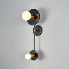 two black and gold wall lights against a gray background