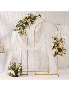 a white and gold wedding arch decorated with flowers