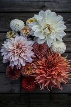 an arrangement of flowers sitting on top of a wooden table