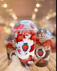 two plastic cups filled with strawberries and ice cream