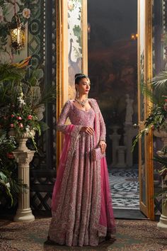 a woman in a pink gown standing next to a doorway