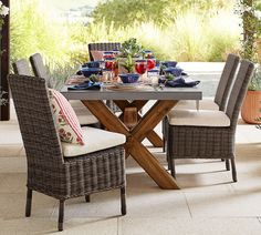 an outdoor dining table with chairs and plates on it