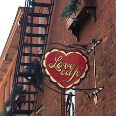 a sign on the side of a building that says love cafe with a heart in it