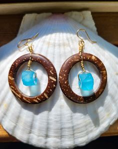 These coconut shell hoop earrings feature a Caribbean blue glass piece made on the island of Java. They are hand wrapped with 14 kt gold filled wire and hang from 14 kt gold filled ear hooks. Coconut shell hoop is 1.5 inches in diameter and the glass piece is approximately 1 cm at widest point.  Due to the natural nature of the coconut shell and handmade nature of the glass, each earring set will vary slightly in size, color, shape, and thickness. Each pair is completely unique. Every purchase r Turquoise Wire Wrapped Earrings For Beach, Blue Hoop Jewelry For The Beach, Blue Small Hoop Jewelry For Beach, Blue Small Hoop Jewelry For The Beach, Beach Hoop Earrings Wire Wrapped, Beach Wire Wrapped Hoop Earrings, Beach Hoop Earrings With Wire Wrapping, Handmade Hoop Jewelry For Vacation, Handmade Small Hoop Jewelry For Vacation